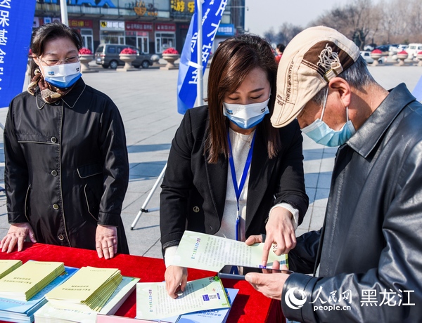 黑龍江省醫(yī)保局工作人員為群眾發(fā)放宣傳單。人民網(wǎng) 張哲鑫攝