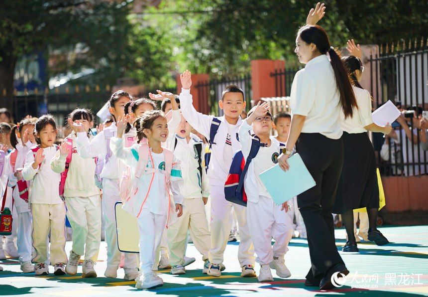 哈爾濱市紅巖小學一年級新生在老師的指引下有序進入校園。人民網(wǎng)記者 蘇靖剛攝