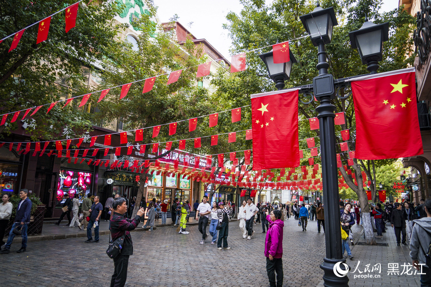 哈爾濱中央大街掛起了五星紅旗，許多市民游客在此拍照留念。人民網(wǎng)記者 張哲鑫攝